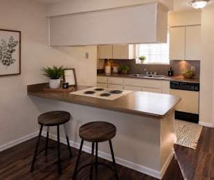 Floor Plan  A kitchen with a white countertop and brown stools.