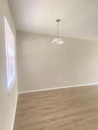A room with a light hanging from the ceiling and a window on the left. at Imperial Gardens Apartments, Clearwater, FL