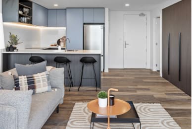 a living room with a couch and a kitchen with stools