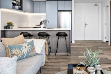 a living area with a couch and a kitchen with bar stools