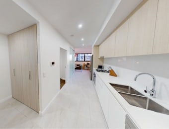 A modern kitchen with white cabinets and a long white counter.