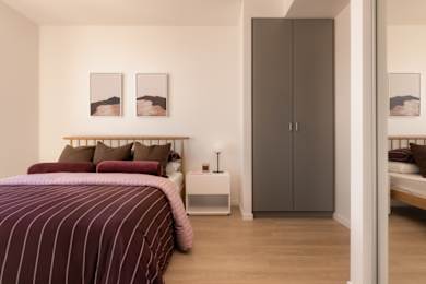 A bedroom with a bed, nightstand, and two framed pictures on the wall.