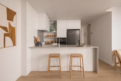 A kitchen with a white counter and two bar stools.