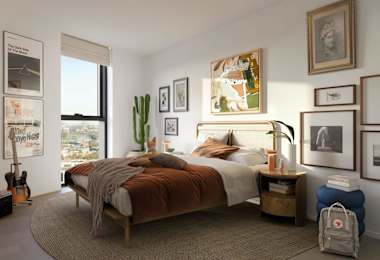 A bedroom with a large bed and a cactus plant on the windowsill.