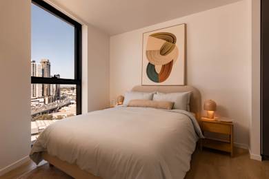 A bedroom with a large bed and a large window overlooking a cityscape.