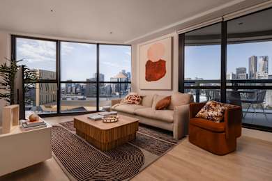 A modern living room with a view of the cityscape outside the large windows.