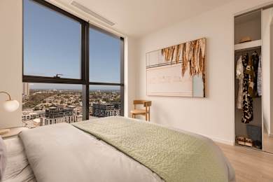 A bedroom with a large bed and a view of the city.