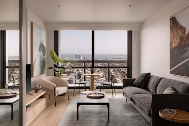 A living room with a grey couch and a view of the city.