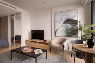 A living room with a television, a chair, a table, and a painting on the wall.