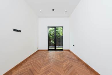 A room with a wooden floor and a glass door leading outside.