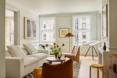 A living room with a white couch, a wooden table, and a yellow chair.
