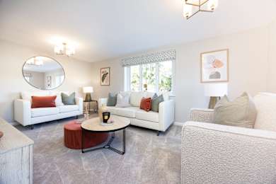 A living room with white furniture and a round mirror on the wall.