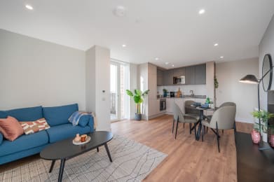 a living room with a blue couch and a table and a kitchen