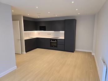 A kitchen with black cabinets and a wooden floor.