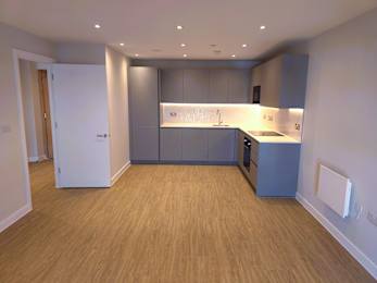 A kitchen with wooden floors and grey cabinets.