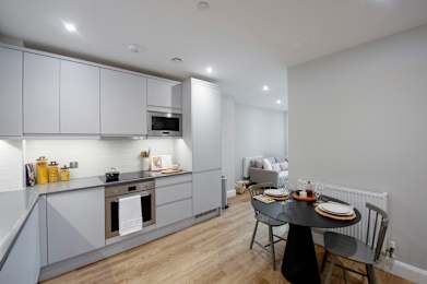 A modern kitchen with a dining table set for two.