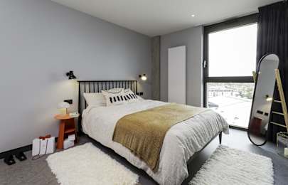 A bedroom with a large bed and a white rug at Beton Apartments, Wembley