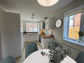 Floor Plan  A kitchen with a table and chairs in the foreground and a window with a view of a fence and a building in the background.