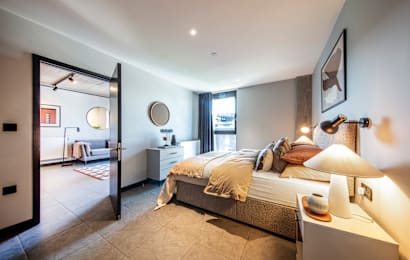 A bedroom with a bed, nightstand, and lamp.