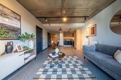 A living room with a grey couch and a checkered rug.