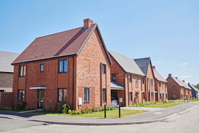Floor Plan  A row of red brick houses with a clear blue sky above.