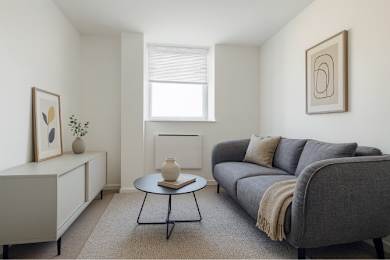 A living room with a grey couch, a coffee table, and a window.
