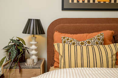 A bedroom with a bed, a lamp, and a potted plant.
