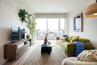 A living room with a green couch and a flat screen TV.