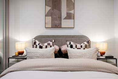 A bed with a grey headboard and two pillows with a checkered pattern.