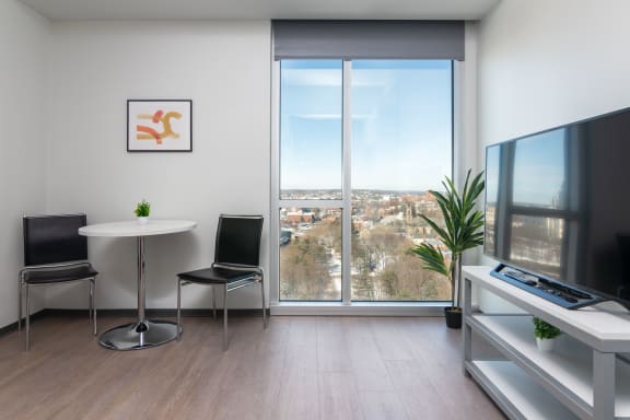 Floor Plan  a living room with a large window and a table with chairs and a television
