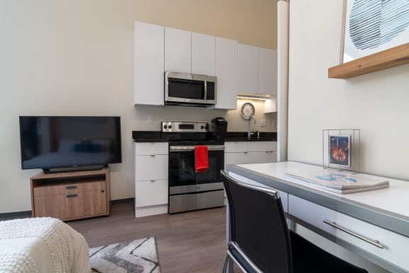 Floor Plan  a kitchen with white cabinets and black and white appliances and a table and chairs