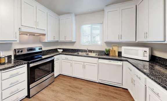Floor Plan  A kitchen with white cabinets and black countertops.