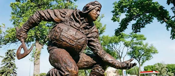 A bronze statue of a man holding a horseshoe.