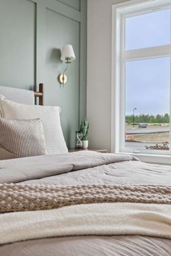 Floor Plan  A bedroom with a bed, pillows, a lamp, and a window overlooking a parking lot.