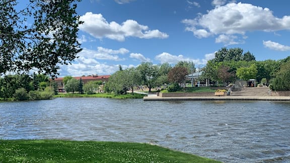 A serene river landscape with a dock and buildings in the distance.