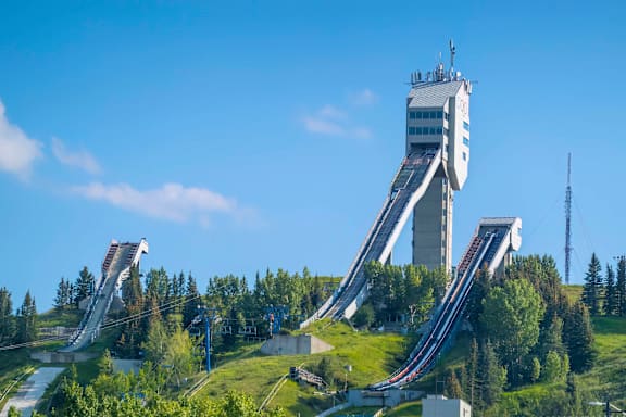A large, multi-level ski jump in a clear blue sky.