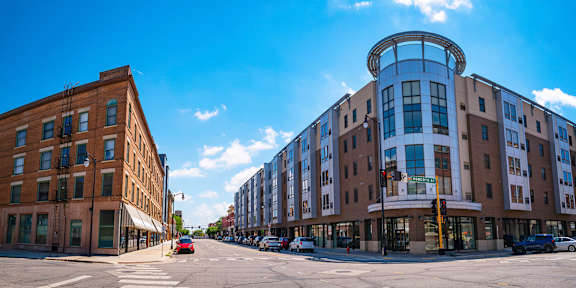 A street view with a red car and a building with a round window.