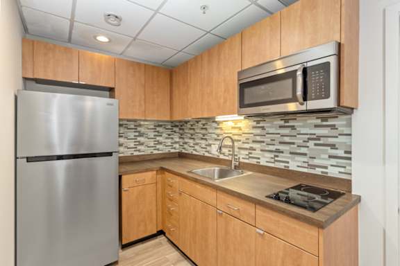 Floor Plan  A kitchen with a stainless steel refrigerator and a microwave above the stove.