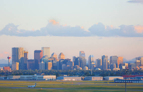 An airplane is on the runway at an airport with a city skyline in the background.