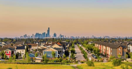 A suburban neighborhood with houses and a city skyline in the distance.