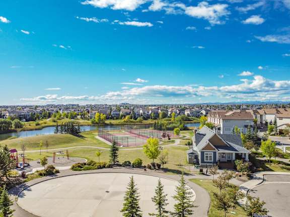 A park with a basketball court and a house in the foreground.