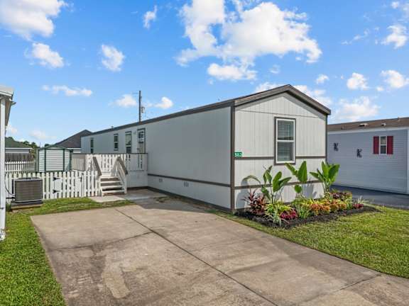Floor Plan  A grey house with a white picket fence and a green plant in front.