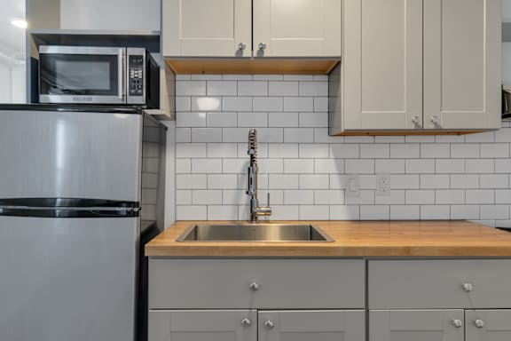 Floor Plan  A kitchen with a stainless steel refrigerator, a microwave, and a sink with a wooden countertop.
