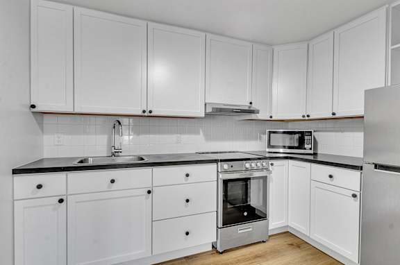 Floor Plan  A kitchen with white cabinets and a black countertop.