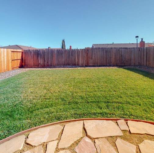 A backyard with a wooden fence and a stone pathway.