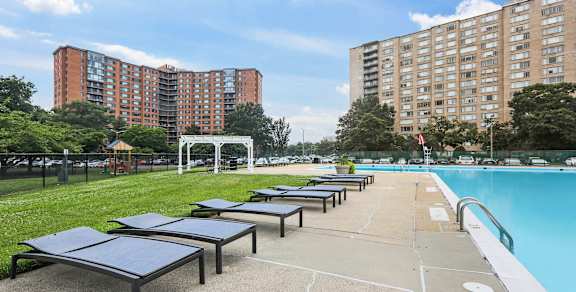 A sunny day at the pool with loungers and buildings in the background.