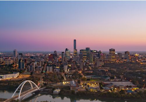 A cityscape at dusk with a bridge over a river.
