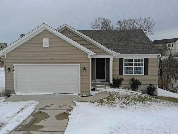Floor Plan  A house with a garage door and a driveway covered in snow.