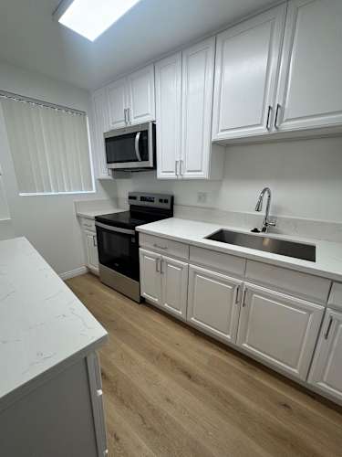 Floor Plan  A kitchen with white cabinets and a black stove top oven.