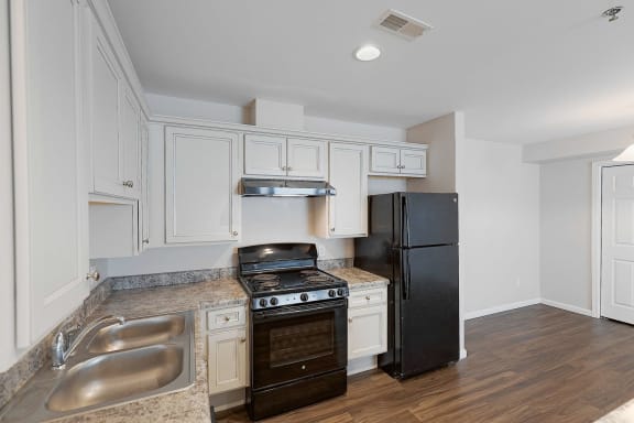 Floor Plan  a kitchen with white cabinets and a black refrigerator